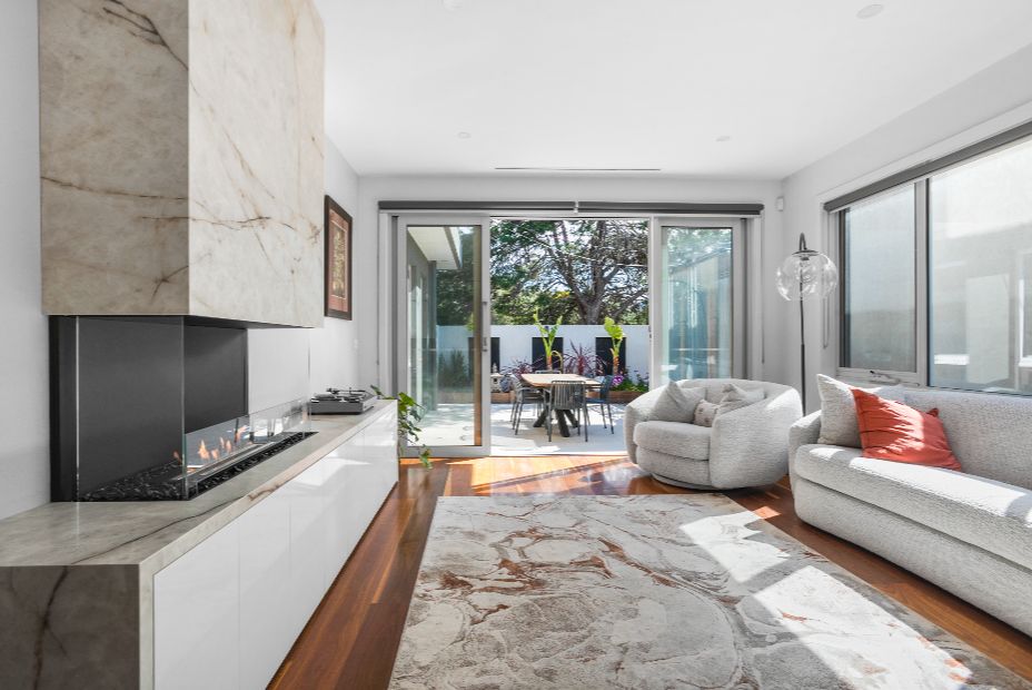 Modern living room with an ethanol fireplace, sofa, and large windows.